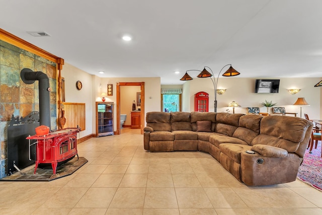 living area with a wood stove, visible vents, recessed lighting, tile patterned floors, and baseboards