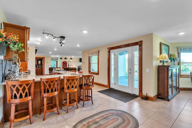 kitchen with a peninsula, open floor plan, light countertops, light tile patterned floors, and baseboards