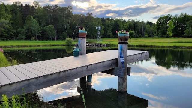 view of dock featuring a wooded view and a water view