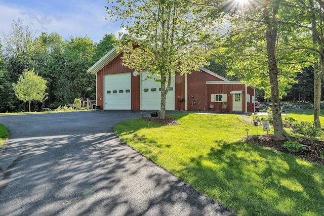 view of front of home with a garage, an outdoor structure, a front yard, and aphalt driveway