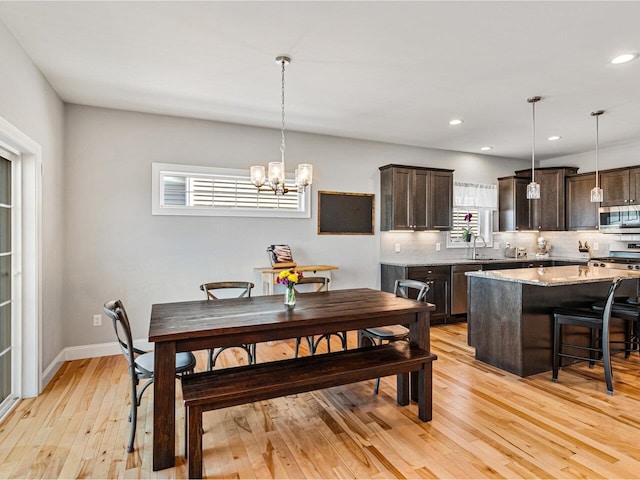 dining space featuring baseboards, a notable chandelier, light wood finished floors, and recessed lighting