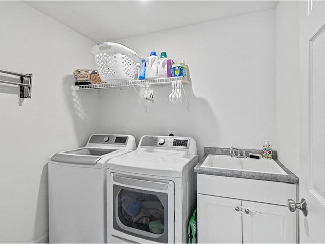 washroom with cabinet space, independent washer and dryer, and a sink