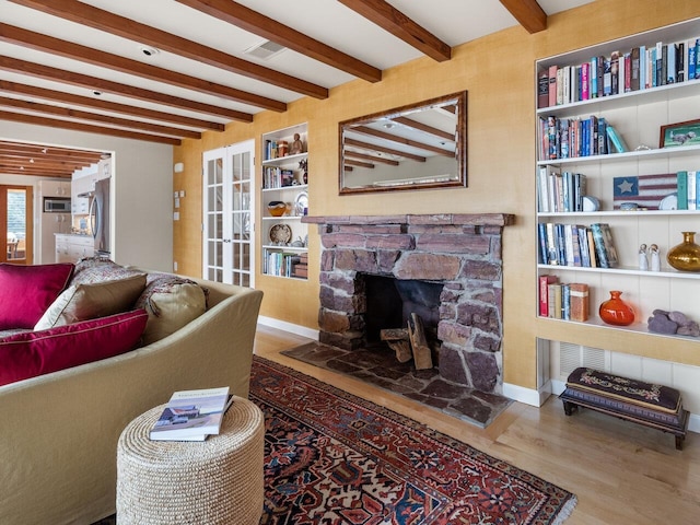 25 Oakledge Dr, Burlington, VT 05401 - living room featuring beam ceiling, wood finished floors, visible vents, built in shelves, and a stone fireplace