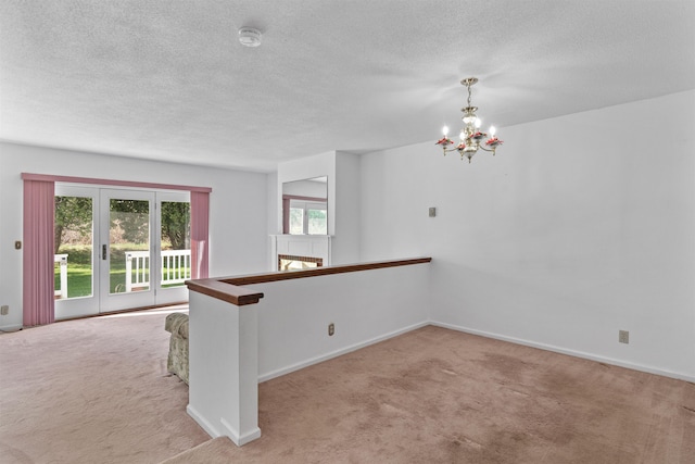 carpeted spare room featuring baseboards, a notable chandelier, and a textured ceiling