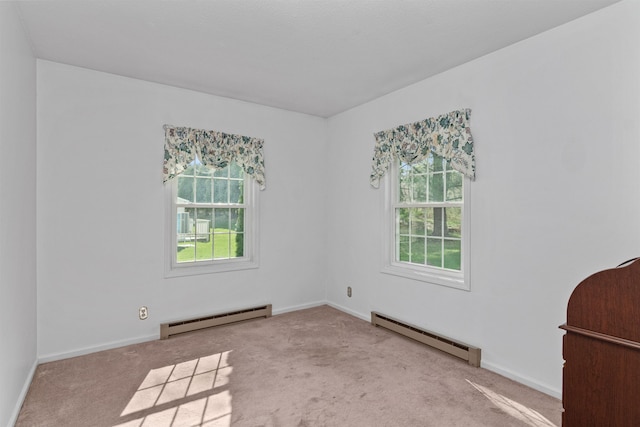 carpeted spare room with a baseboard heating unit, a healthy amount of sunlight, baseboards, and baseboard heating