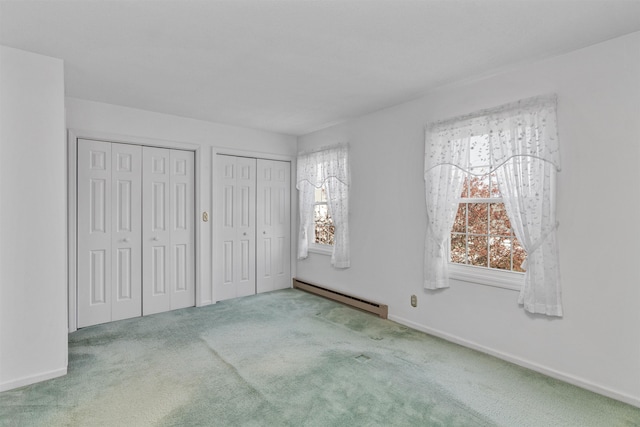 unfurnished bedroom with multiple closets, carpet flooring, baseboards, and baseboard heating