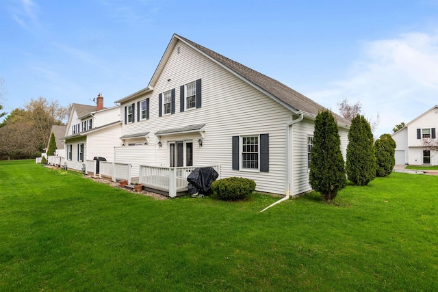 rear view of property with a lawn, a deck, and a chimney