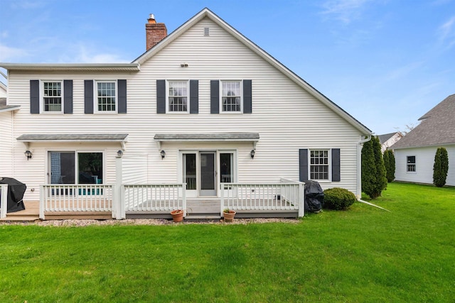 back of house with a lawn, a chimney, and a wooden deck