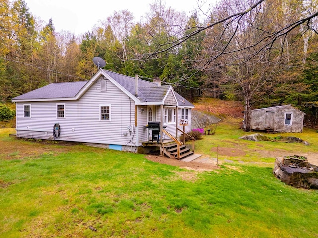 rear view of property with a yard, a chimney, an outdoor structure, and a shingled roof