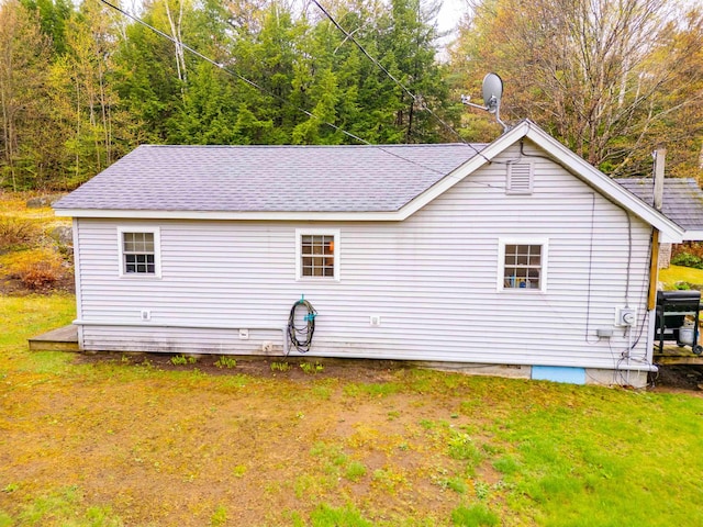 rear view of property with a lawn and a shingled roof
