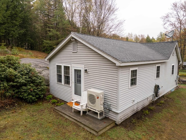 exterior space featuring roof with shingles, a wooden deck, and ac unit