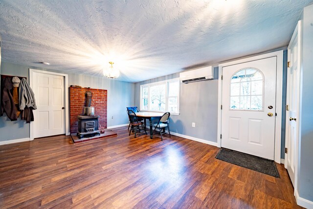 foyer entrance featuring an AC wall unit, baseboards, a healthy amount of sunlight, and wood finished floors