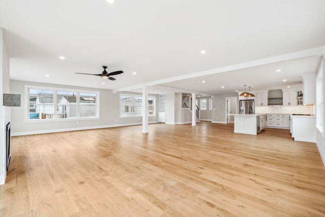 unfurnished living room featuring baseboards, ceiling fan, and recessed lighting