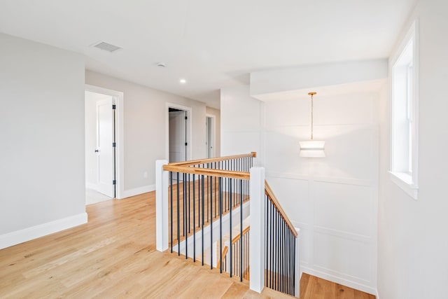 hallway featuring recessed lighting, baseboards, visible vents, wood finished floors, and an upstairs landing