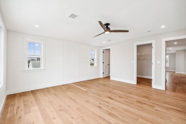 unfurnished bedroom featuring a walk in closet, light wood-style floors, a ceiling fan, and recessed lighting