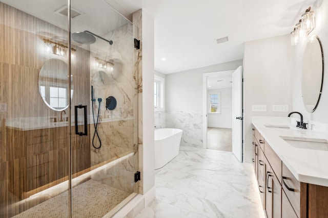 bathroom featuring a marble finish shower, marble finish floor, a freestanding bath, and a sink