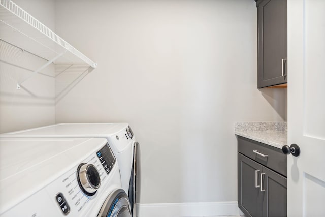 laundry room with baseboards, independent washer and dryer, and cabinet space