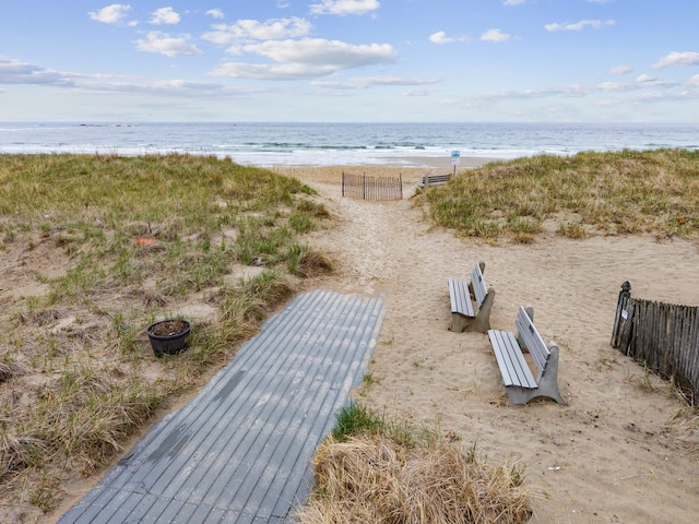 exterior space featuring fence, a water view, and a beach view