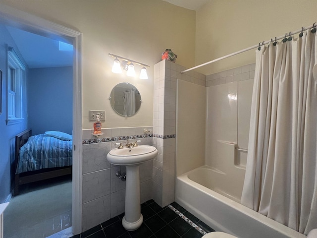 bathroom featuring tile walls, shower / bath combo with shower curtain, a sink, tile patterned floors, and a wainscoted wall
