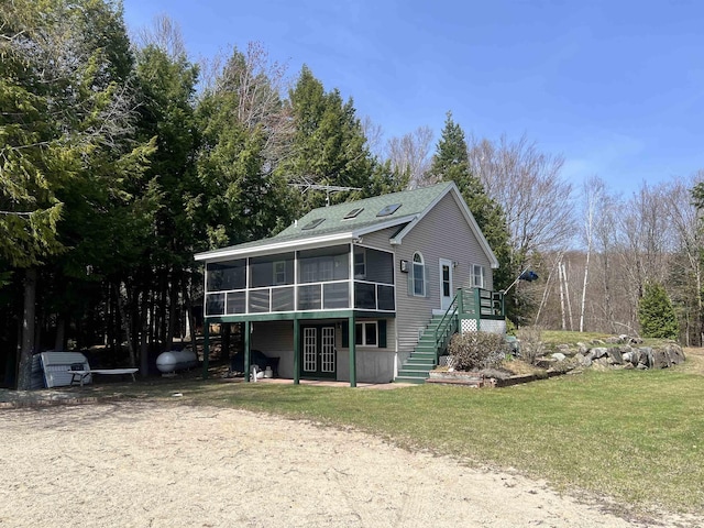 exterior space featuring a yard, stairway, a wooden deck, and a sunroom