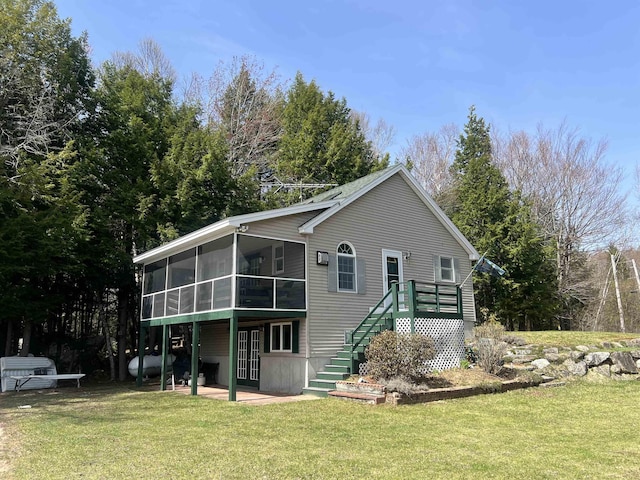 rear view of property featuring a lawn, stairway, a patio, and a sunroom
