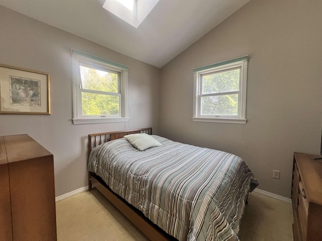 bedroom featuring baseboards and vaulted ceiling with skylight