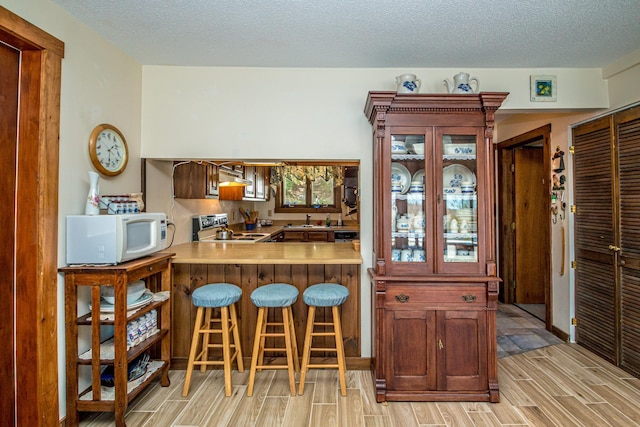 26 Private W 4, Maidstone, VT 05905 - kitchen featuring a breakfast bar, white microwave, exhaust hood, wood finish floors, and electric stove
