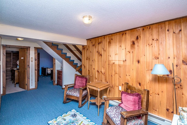 26 Private W 4, Maidstone, VT 05905 - sitting room with a baseboard radiator, a textured ceiling, wooden walls, stairway, and carpet floors