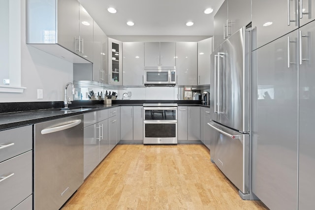 kitchen with dark countertops, appliances with stainless steel finishes, gray cabinets, and a sink