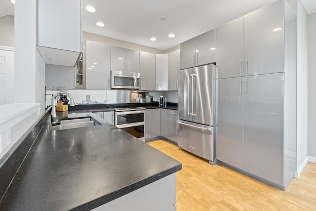 kitchen featuring recessed lighting, gray cabinets, stainless steel appliances, and a sink