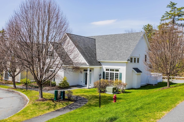 traditional home featuring a front lawn and roof with shingles