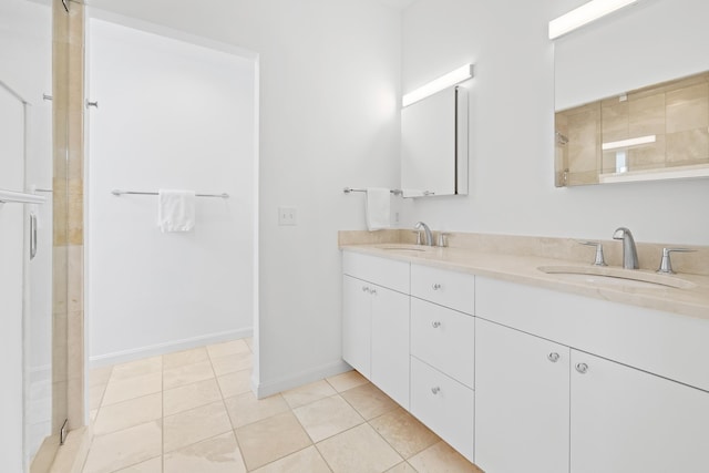 bathroom with a shower, tile patterned floors, double vanity, and a sink