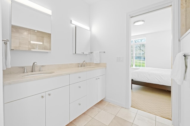 ensuite bathroom with double vanity, connected bathroom, baseboards, and a sink