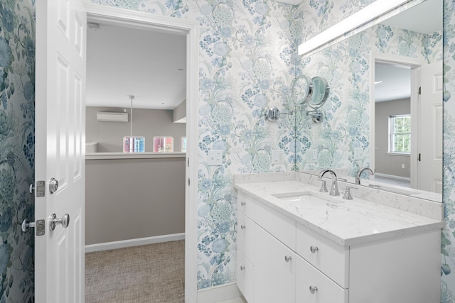 bathroom featuring wallpapered walls, baseboards, vanity, and a wall mounted AC