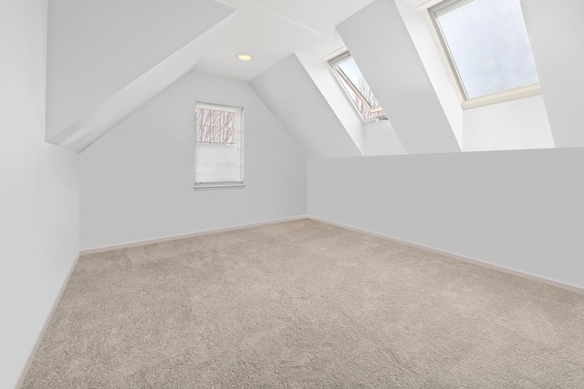 additional living space featuring baseboards, lofted ceiling with skylight, and carpet