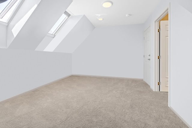 bonus room with baseboards, vaulted ceiling with skylight, and carpet floors