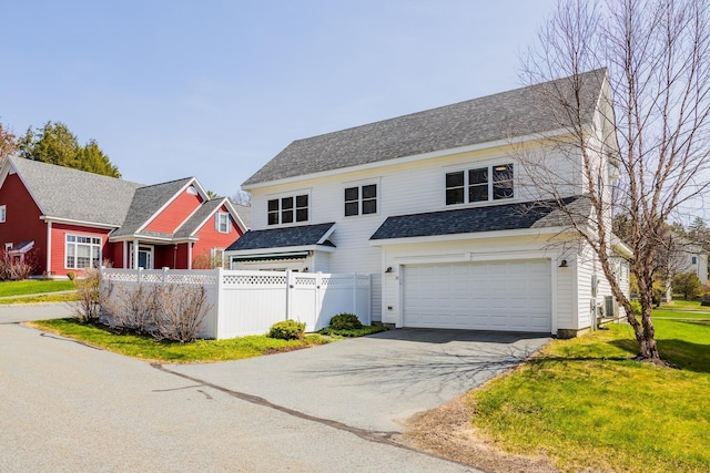 traditional home featuring a garage, fence, aphalt driveway, a shingled roof, and a front yard