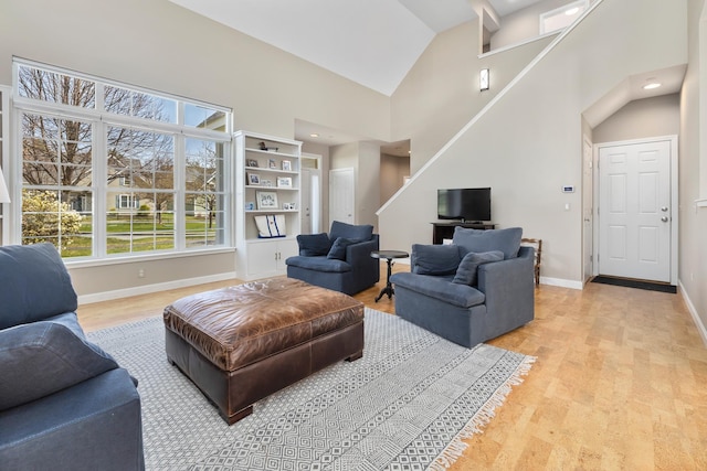 living area featuring light wood finished floors, lofted ceiling, and baseboards