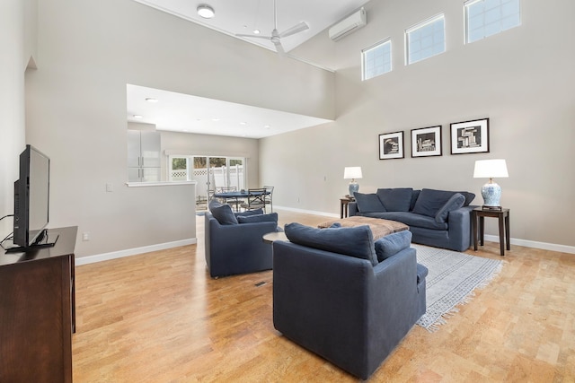 living room featuring baseboards, light wood-style flooring, and a high ceiling
