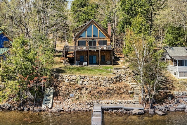 rear view of property featuring a chimney and a deck with water view
