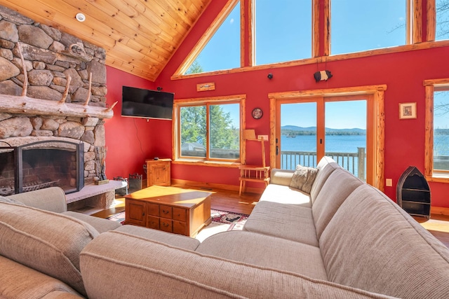 living room featuring baseboards, a fireplace, high vaulted ceiling, and wood finished floors