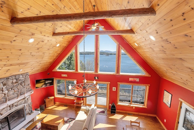 living room with wood ceiling, plenty of natural light, wood finished floors, and a stone fireplace
