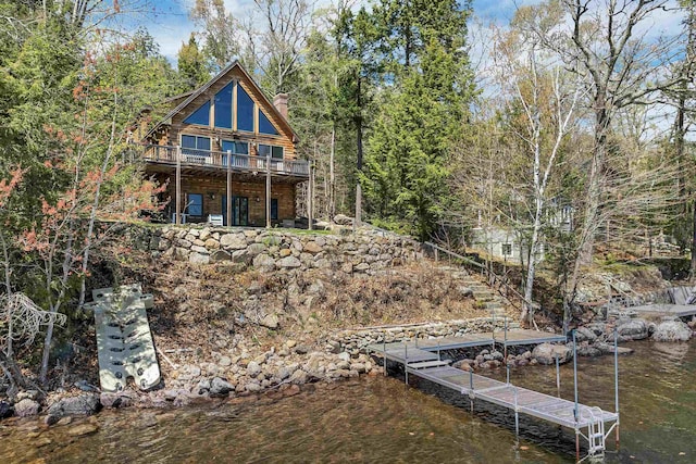 back of house with a chimney, a water view, and log siding