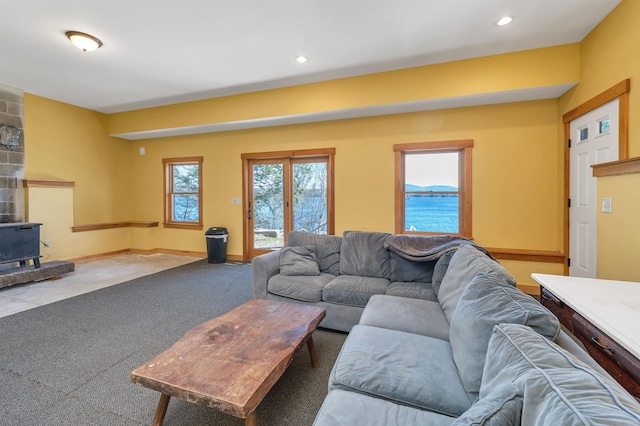 carpeted living area with baseboards, a wood stove, and recessed lighting