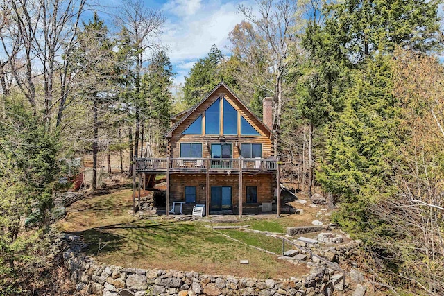 back of property with a chimney, a deck, and a yard