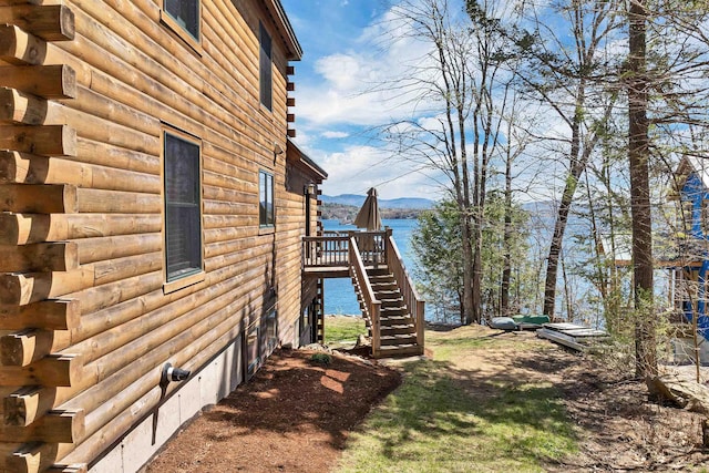 view of side of home featuring a deck with water view, log siding, and stairs