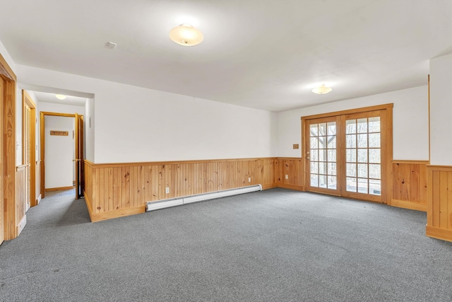 empty room with wooden walls, carpet floors, a wainscoted wall, and baseboard heating
