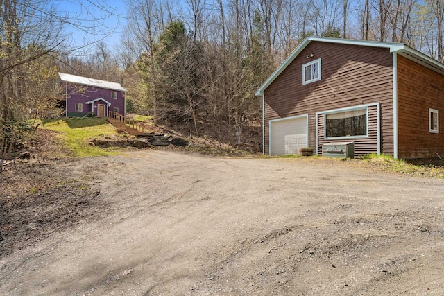 view of side of property with dirt driveway and a barn