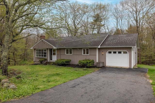 single story home with aphalt driveway, a garage, a front lawn, a chimney, and a shingled roof