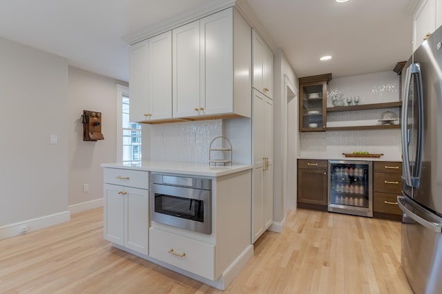 kitchen with wine cooler, light wood-style floors, light countertops, and freestanding refrigerator